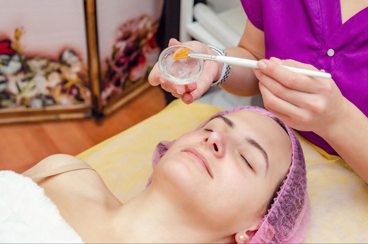 Cosmetologist applying a chemical peel to a client's face in a UAE clinic